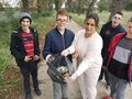 Grupa uczniów z nauczycielem znajdują się w otoczeniu zieleni mają założone rękawiczki prezentują worek z zebranymi śmieciami 