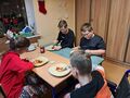 Uczniowie siedzą przy stole i jedzą naleśniki 