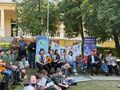 zaproszeni goście i harcerze wspólnie śpiewają i wykonują pląsy wokół ogniska w parku z tyłu banery promocja zdrowia powiat krotoszyński
