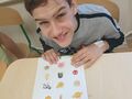 uczeń siedzi przy ławce w klasie i wypełnia kartę pracy