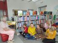 uczniowie przebywaja w bibliotece i sluchaja czytanej przez pania bibliotekarke bajki