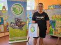 laureat konkursu pozuje do zdjęcia w tle wystawa prac i baner powiatu krotoszyńskiego