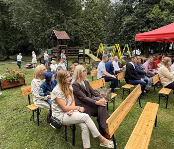 nauczyciele uczniowie rodzice siedzą w ławkach w parku