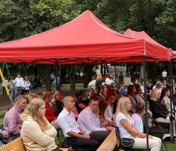 uczniowie nauczyciele rodzice siedzą w ławkach w parku