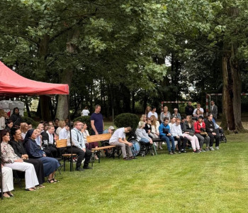 rodzice uczniowie i nauczyciele siedzą w ławkach w parku