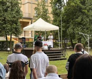 uczniowie stoją na mszy świętej w parku