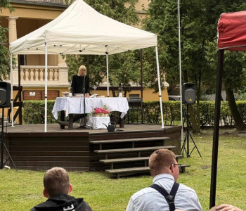 Pani Dyrektor przemawia do mikrofonu w parku na scenie