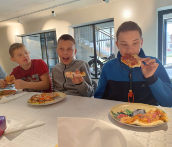 kolejni uczniowie jedzą pizzę