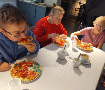 uczniowie zajadają sie pizzą przy stole