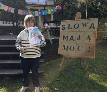 Dziewczynka stoi przed sceną i trzyma w ręce dyplom_