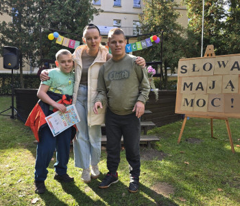 Pani nauczycielka stoi z dwoma uczniami, jeden z chłopców trzyma dyplom_